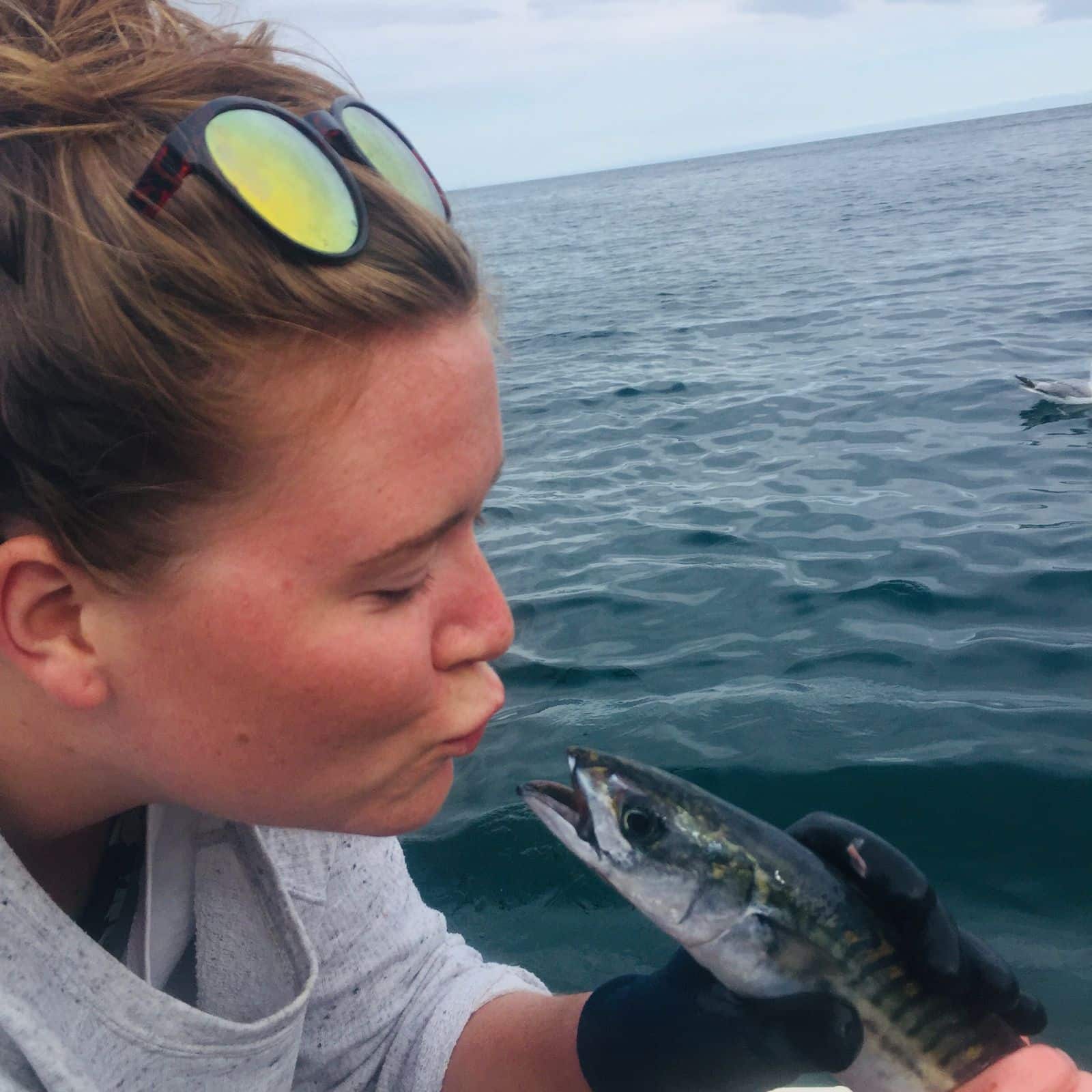 Local girl kissing a handline caught mackerel Looe Cornwall